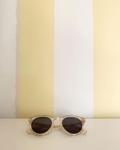 a pair of sunglasses sitting on top of a table next to a yellow striped wall