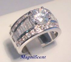 an engagement ring with two baguettes and diamonds on it's sides, sitting on top of a white surface