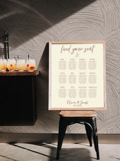 a seating chart is displayed on a small table in front of a wall with candles