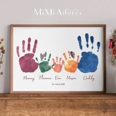 a family handprint is displayed on a shelf next to a vase with flowers in it