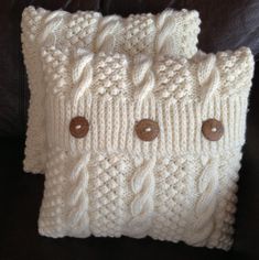 two white knitted pillows with buttons on them