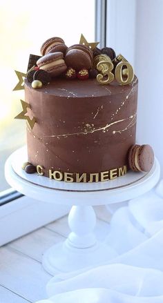 there is a chocolate cake with gold decorations on the top and bottom, sitting in front of a window