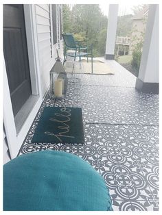 the front porch is decorated with black and white tiles, blue chairs, and a teal rug