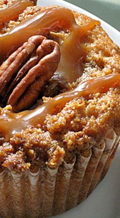 a cupcake with pecans and caramel drizzled on top sitting on a plate