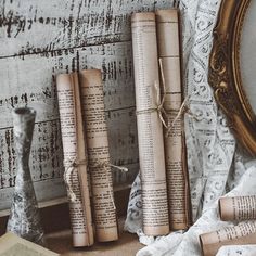 three rolled up books sitting on top of a table next to an old mirror and some other items