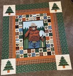 there is a quilt on the floor that has a bear holding a pickle in it's hand