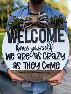 a man holding a sign that says welcome home, because yourself we are as crazy as they come