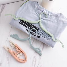 two pairs of scissors are laying next to a t - shirt on a marble surface