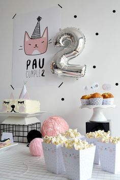 a table topped with lots of cakes and cupcakes next to a number 2 sign