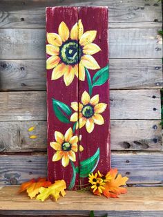 a wooden sign with sunflowers painted on it