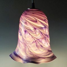 a purple and white glass light hanging from a ceiling