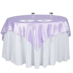 two wine glasses sitting on top of a table covered in a purple and white cloth