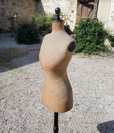 a mannequin head on a wooden stand in front of an old stone building