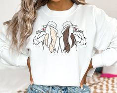 a woman wearing a white sweatshirt with two horses on it