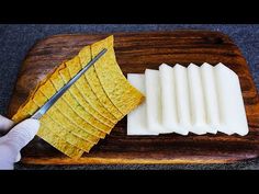 a person cutting up some food on a wooden board with a knife and tortilla chips