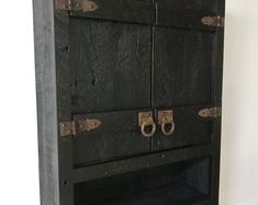 an old black wooden cabinet with metal handles