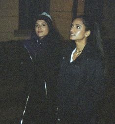 two women standing next to each other at night