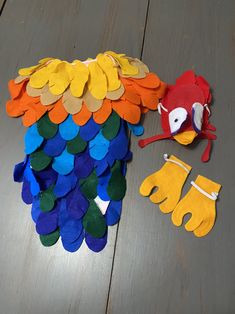 a pair of yellow gloves sitting on top of a wooden floor next to a pile of colorful felt