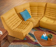 a yellow couch and chair sitting on top of a wooden floor next to a coffee table