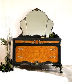 an antique dresser with a mirror on top and plants in front of it next to a white rug