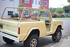 an old yellow truck parked on the side of the road in front of a building