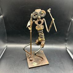 a metal sculpture of a skeleton holding a stick