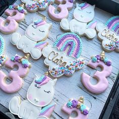 decorated cookies are arranged on a tray with the numbers 3, 5, and unicorns