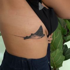 a woman's stomach with a small tattoo of a manta ray on it