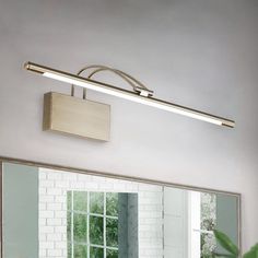 a bathroom with a large mirror and lights on the wall next to a sink in front of a potted plant