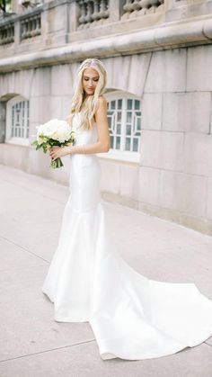 a woman in a white wedding dress holding flowers