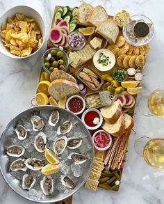 a platter filled with oysters, bread and crackers next to wine glasses