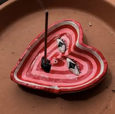 a heart shaped bowl with two black and white birds on it, sitting in the middle of a planter