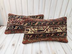 two decorative pillows sitting on top of a white wooden floor next to each other,