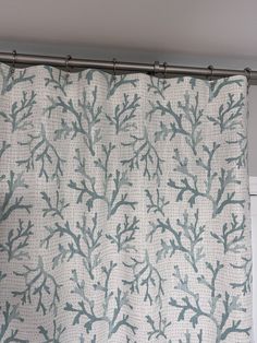 a shower curtain with blue and white corals on the outside, hanging from a metal rod