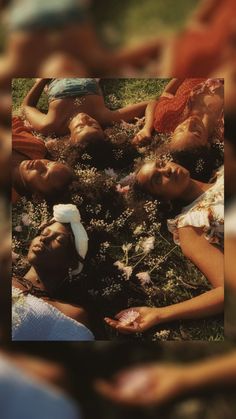 a group of people laying on top of a lush green field next to each other