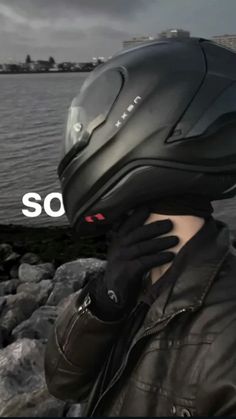 a person wearing a motorcycle helmet with the word so on it's face next to some rocks