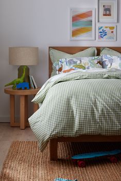 a bed with green and white checkered comforter on top of it next to a wooden night stand