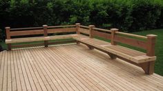 two wooden benches sitting on top of a wooden deck next to grass and trees in the background