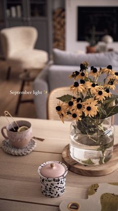 a vase filled with yellow flowers sitting on top of a wooden table next to a cup