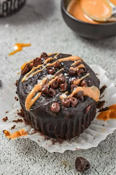 a chocolate cupcake with caramel drizzle on top, sitting on a paper wrapper