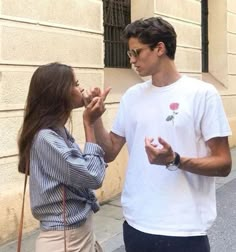 a man standing next to a woman on the side of a street talking to each other