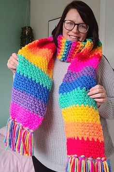 a woman is wearing a multicolored knitted scarf with fringes on it