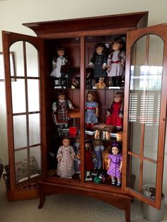 a wooden cabinet filled with lots of dolls