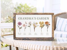 a wooden framed sign with flowers on it sitting on a table next to a wicker chair