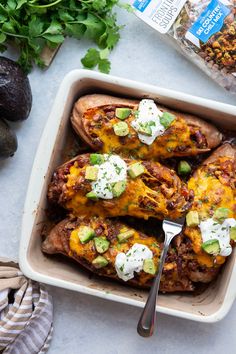 baked potato skins in a baking dish with avocado and sour cream