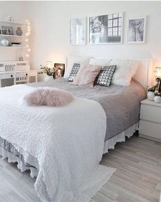 a bedroom with white walls and wooden flooring is decorated in soft pink and gray tones