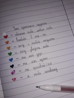 writing on lined paper with colored hearts and words written in cursive handwriting, next to a pen