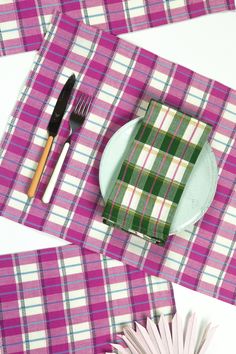 the table is set with pink and green plaid placemats, silverware, and napkins