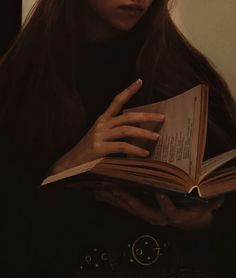 a woman is holding an open book in her hands