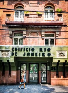 a woman walking in front of a building with a sign on it's side